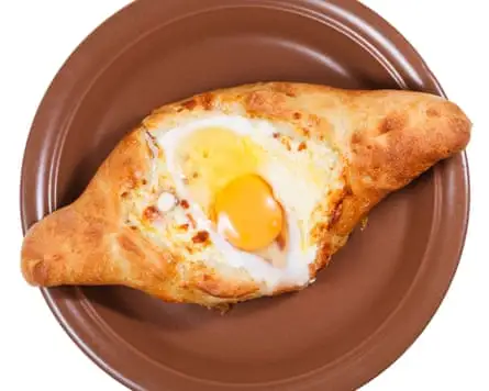 A pastry filled with cheese and topped with a soft-boiled egg and butter