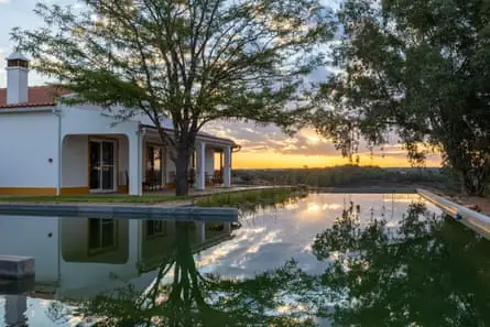 A whitewashed house surrounded by a pool
