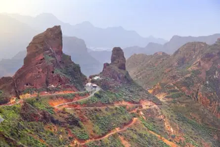 Winter view of Gran Canaria landscape - rocky pinnacles a road zigzagging and distant mountains in sunshine
