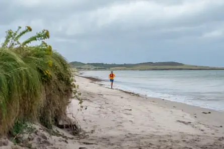 Man runs on sandy beach in dull weather