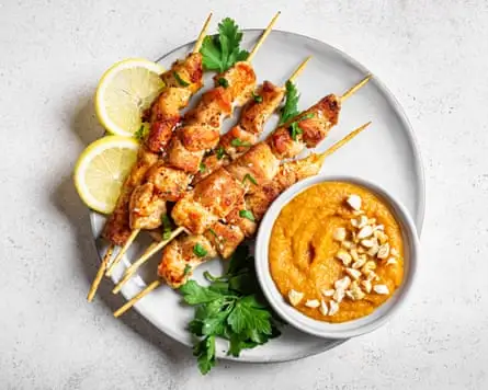 Grilled chicken pieces on wooden skewers with spicy peanut sauce