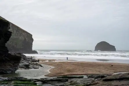 Cornish beach in winter with distant people and dog and a little rocky islet offshore