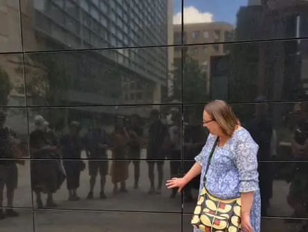 Woman with blue shirt admires reflecting black wall in London