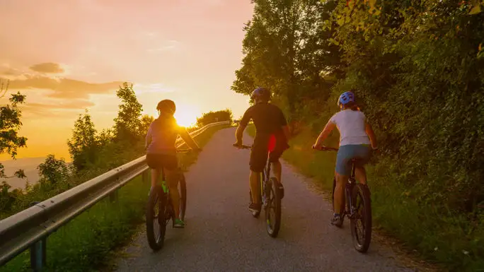 Travelers explore the rural landscape on electric bikes at sunrise.