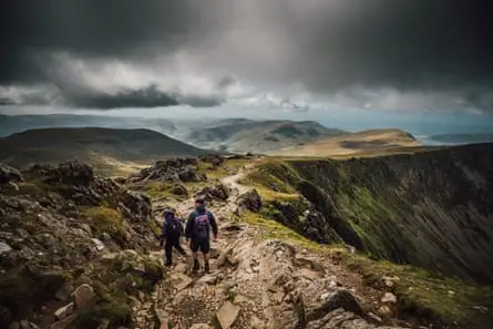 Hikers on a Welsh mountain top underneath grey skies.