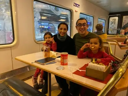 Family on a train in the dining car smiling at camera - two young daughters, mother and father