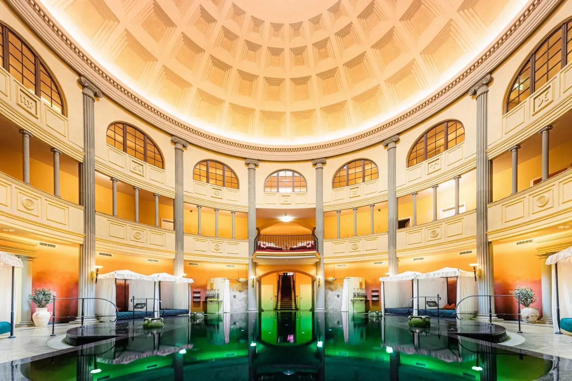 Hohe Säulen, eine imposante Kuppel und ein in grünes Licht getauchtes Thermalbecken vermitteln römisches Flair im Spa.