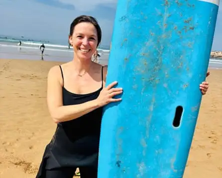 Young woman smiling holding aquamarine surf 