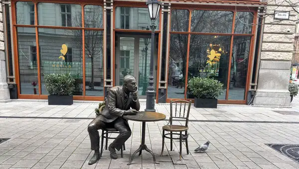 A statue located near cafes in Budapest signals the importance of historic coffeehouse culture for the city's intellectuals and literary community.