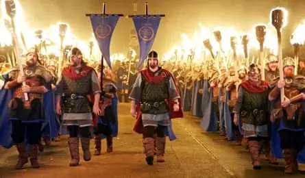 Men in Viking costumes marching with standards and holding up flaming torches