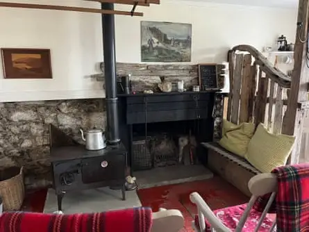 A black stove surrounded by wooden furniture with tartan blankets